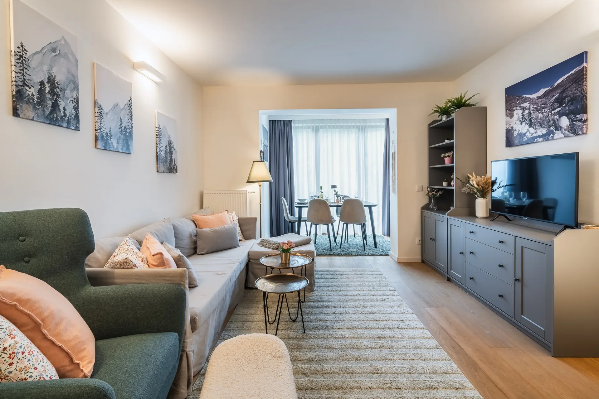Modernes Wohnzimmer mit grünem Sofa, orange Akzenten und Bergkunst im Rosie Design Chalet Nr. 2 Kärnten – professionelle Ferienwohnung Fotografie – Mathias Prägant Photography