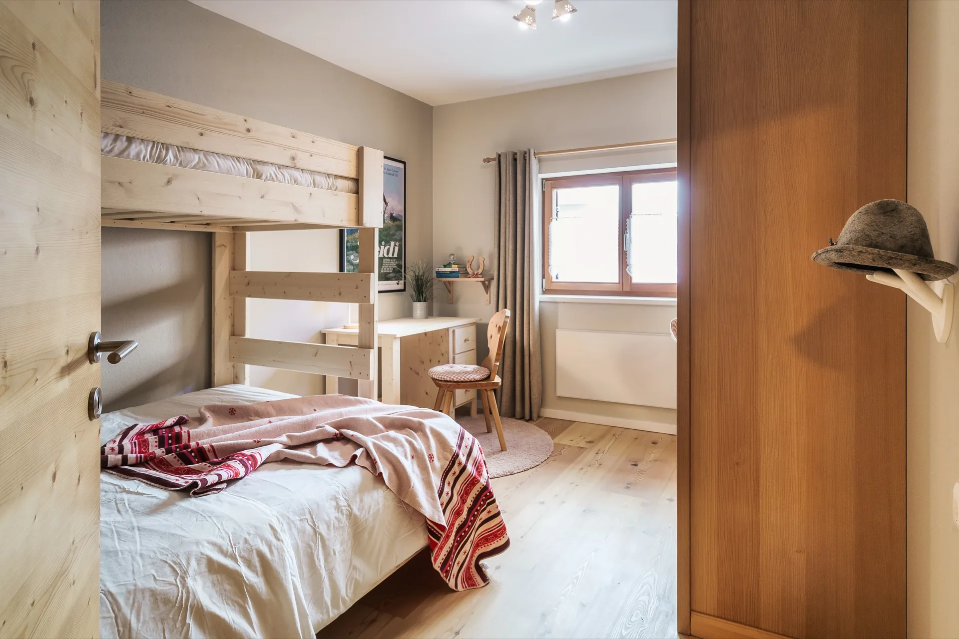 Helles Kinderzimmer mit Etagenbett aus hellem Holz, Schreibtisch und alpinen Dekorationen in der Bergfreunde Bad Kleinkirchheim – familienfreundliche Ferienwohnung Fotografie – Mathias Prägant Photography